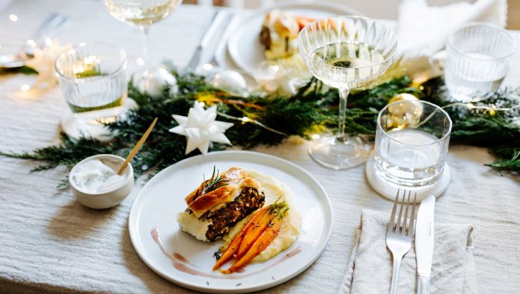 veganer Linsenbraten mit Kartoffelpürree und Karotten auf weihnachtlich gedecktem Tisch