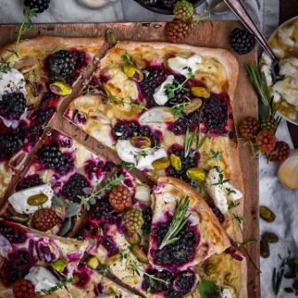 eckiger Flammkuchen mit Brombeeren, Creme und Gewürzen auf Holzbrett dekoriert