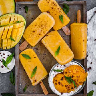 Mangoeis am Stiel mit Mangoeis in Schüssel und Mangos  und Blättern dekoriert 