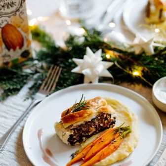 veganer Linsenbraten mit Kartoffelpürree und Karotten auf weihnachtlich gedecktem Tisch