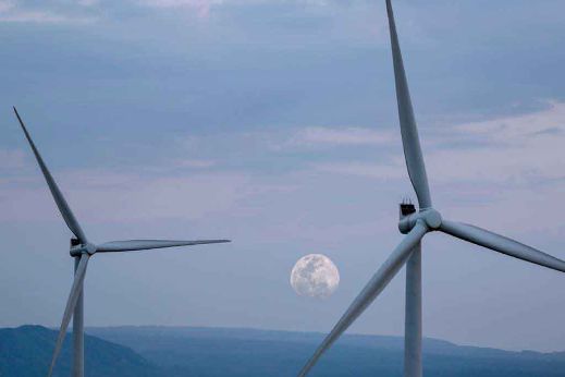 Windräder in Dämmerung mit Mond im Hintergrund