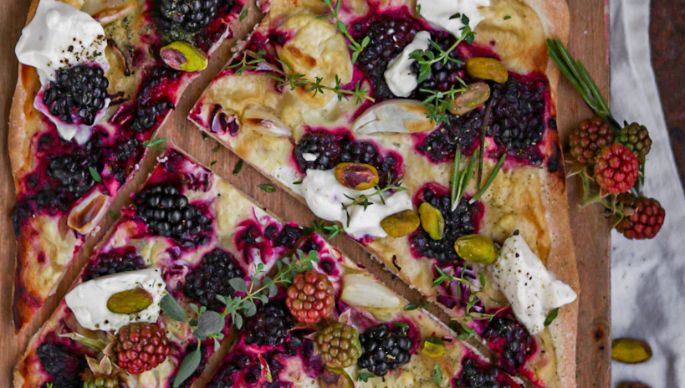 eckiger Flammkuchen mit Brombeeren, Creme und Gewürzen auf Holzbrett mit Dekoration