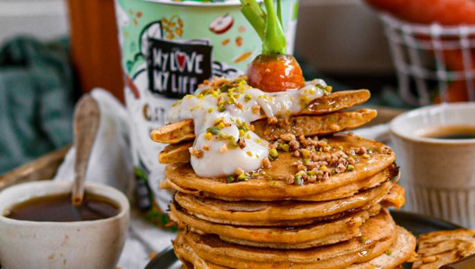 Karottenpancakes auf Teller gestapelt mit MyLove-MyLife Hafer-Joghurtalternative Müsli im Hintergrund
