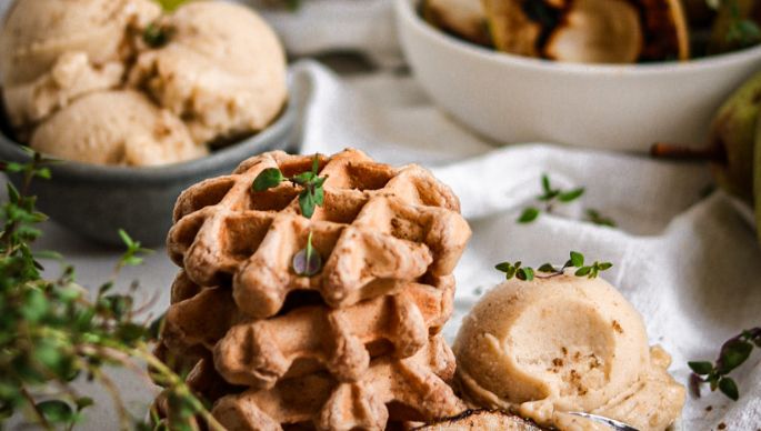 Waffeln mit Birnen-Bananen-Eis und im Hintergrund dekoriert mit Birnen, Eis und Kaffee