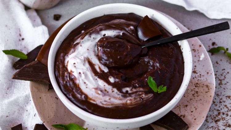 Schokoladenpudding mit Kaffeetassen und Kochcreme rundherum