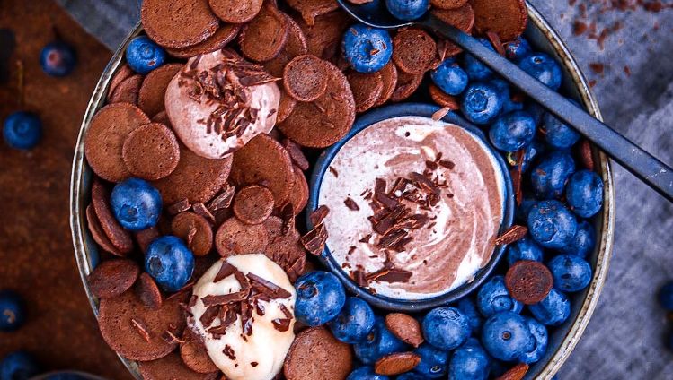 Mini Schokoladen Pancakes in Schüssel mit Heidelbeeren und Creme