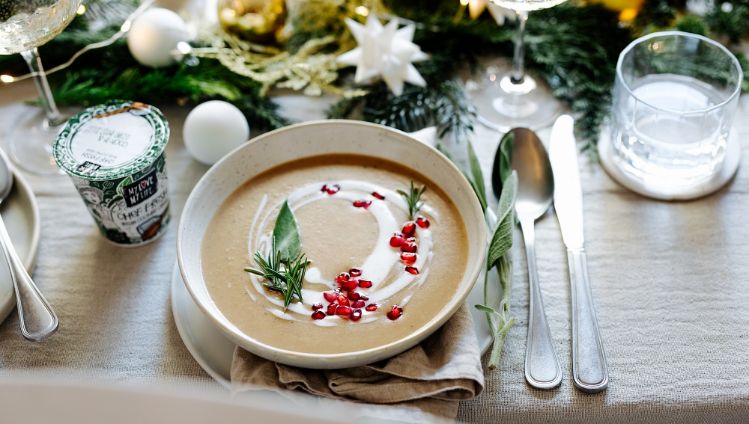 Maronisuppe auf weihnachtlich gedecktem Tisch mit Kochcreme