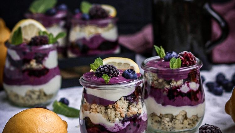 Zitronen-Mohnkuchen mit Beerencreme und weißer Creme geschichtet in Glas mit Dekoration