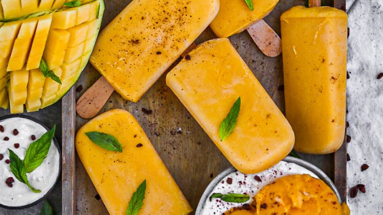 Mangoeis am Stiel mit Mangoeis in Schüssel und Mangos  und Blättern dekoriert 