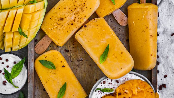 Mangoeis am Stiel mit Mangoeis in Schüssel und Mangos  und Blättern dekoriert 