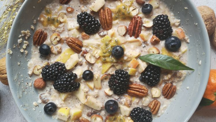 Birchermüsli mit Früchten und Nüssen garniert und Nektarinen und Nüssen rundherum dekoriert