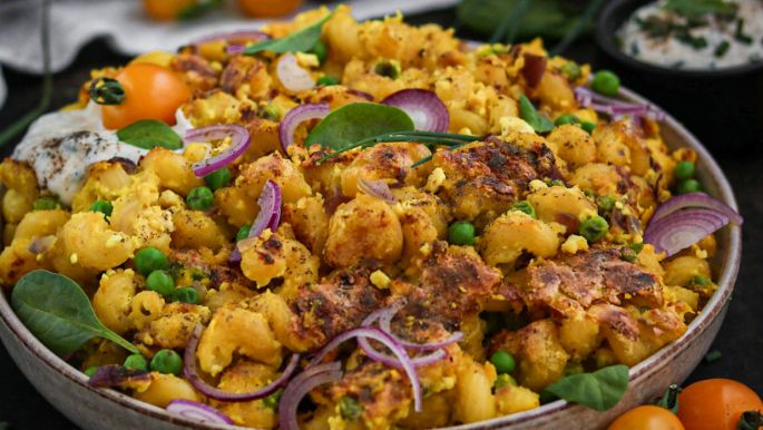 gebratene Nudeln mit "Ei" und Gemüse in Schüssel und rundherum dekoriert mit Früchten