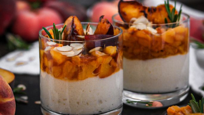 veganer Joghurt-Griess mit Rosmarin Pfirsichen getoppt und Früchten und Rosmarin dekoriert