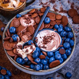 Mini Schokoladen Pancakes in Schüssel mit Heidelbeeren und Creme