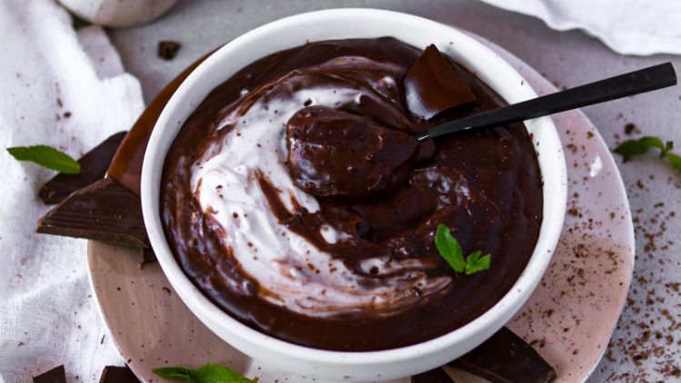 Schokoladenpudding mit Kaffeetassen und Kochcreme rundherum