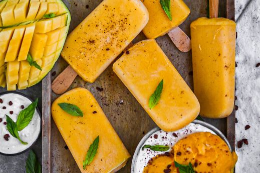 Mangoeis am Stiel mit Mangoeis in Schüssel und Mangos  und Blättern dekoriert